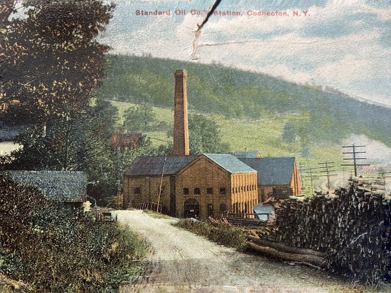 A historic postcard shows the Standard Oil pumphouse.  To safeguard against the possibility of fire, either from combustion of the flammable material being transported or from the eight coal-burning furnaces used to power the oil pumps, the four-story building was framed with nonflammable materials. The walls were brick, the girders iron, the roof sheet metal and the windowsills bluestone.